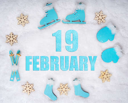 February 19th. Sports set with blue wooden skates, skis, sledges and snowflakes and a calendar date. Day 19 of month. Winter sports concept. Winter month, day of the year concept.の写真素材