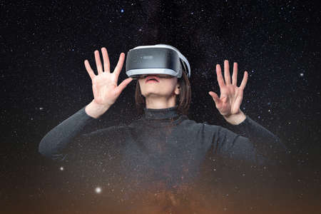 A beautiful woman in a futuristic VR helmet or 3d glasses touches the space. Surprised girl in vr...