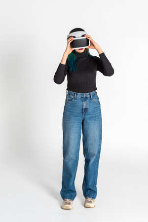 Teen girl using vr headset is in virtual reality cyberspace futuristic white background. The concept of the metaverse, virtual reality, virtual social universe. Future digital technologies.の写真素材