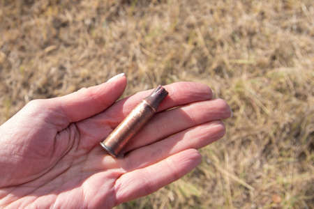 A hand holding an empty bullet casing, close-up. Found empty cartridge case against the background...