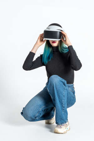A teenager girl puts on a vr helmet to enter the virtual universe isolated on a white background. Lifestyle in the virtual spaceの写真素材