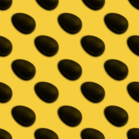 Seamless pattern of halves of black chocolate Easter eggs on a yellow background. Easter sweet chocolate background. Can be used for wallpaper, textile, backgroundの写真素材