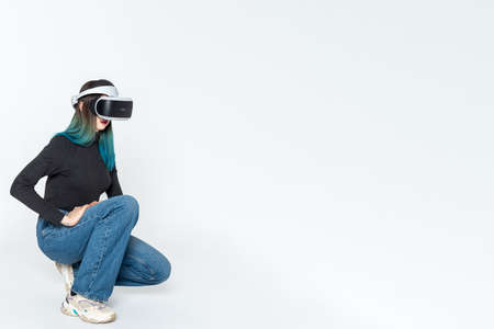 A teenager girl in a vr helmet plays in the virtual universe isolated on a white background. The...
