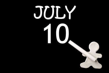 A small white plasticine man writing the date 10July on a black board. Business concept. Education...