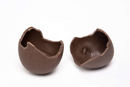 Cracked chocolate Easter eggs on a white background, copy space. Half broken milk chocolate eggs....