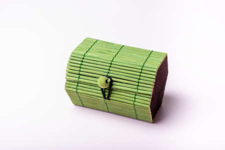 Green toy, closed wicker chest, container on a soft pink background. Chest for secrets, treasure, games with children.の写真素材