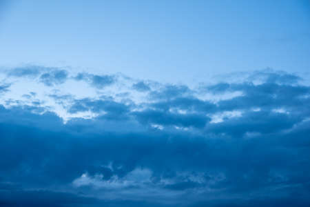 Dark blue evening sky with clouds. Blue hour. Heavenly natural background to overlay on your photos.の写真素材