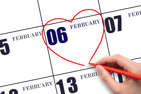 6th day of February. A woman's hand drawing a red heart shape on the calendar date of 6 February. Heart as a symbol of love. Winter month. Day of the year conceptの写真素材