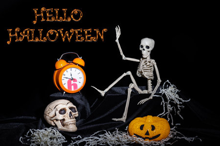 A toy Skeleton crawling out of the grave and waving, greeting, pumpkins with grimaces, an orange...