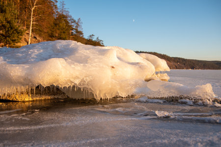 Rows of icicles hang from the stones of the lake shore. Icicles on the beach of the lake on the...