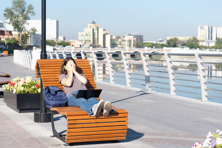 Tired student girl fell asleep on a park bench while studying online, watching online lectures on a...