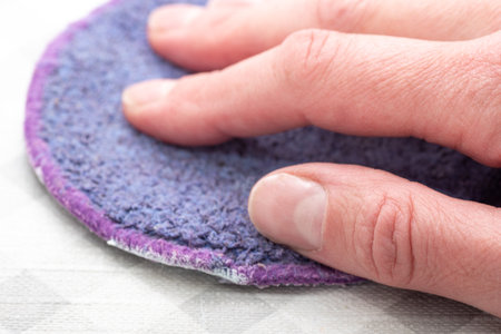 General house cleaning. Wiping the surface from dust with a purple rag, sponge. The hand of a housewife wipes the surface with an absorbent cloth.の写真素材