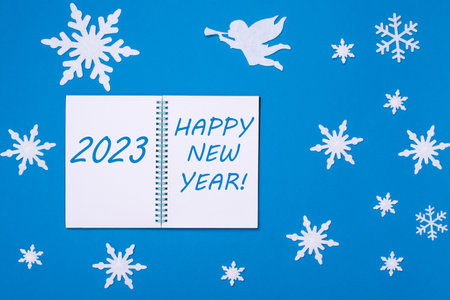 An open notebook diary with the Text 2023 and HAPPY NEW YEAR on a blue background with Christmas...