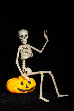 Skeleton sitting on a lamp in the shape of a pumpkin with a grin and waving his hand in greeting on...