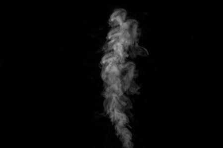 White curly smoke steam rising up is isolated on a black background to overlay on your photos. smoky background. design elementの写真素材
