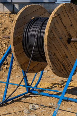 Wooden Coils Of Electric Cable Outdoor. High and low voltage cables. coils industrial wires. Roll of outdoor fiber optic signal shielded cables. Coils of powerful black telecommunications wireの写真素材