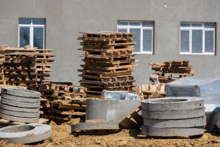Concrete blocks for construction on wooden pallets. A construction site with a building frame in the background and concrete products in the foreground. Building a house from cinder blocks.の写真素材