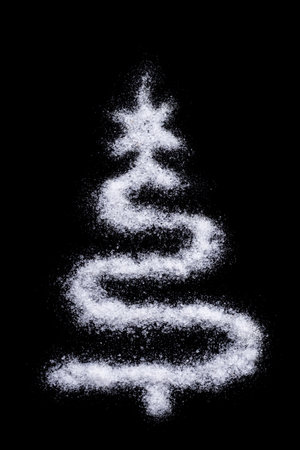 Silhouette of a Christmas tree made of salt like snow on a black background, vertical frame. Creative homemade winter backgroundの写真素材