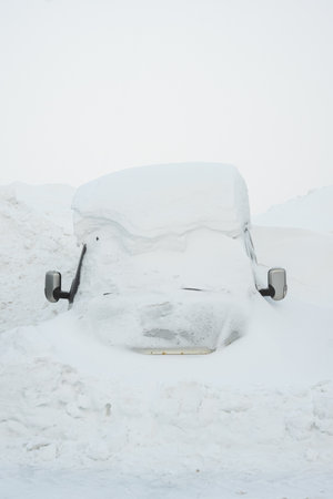 Car under the snow. A lot of snow after a snowfall. The car is completely covered with snow. Danger of snowfall for cars. Winter transport problem. Cold and snowy climate.の写真素材