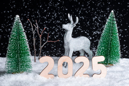 Creative 2025 Christmas card. A toy shining silver deer standing in the snow in the forest among the...