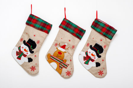 Three Christmas socks with pictures of Rudolph the reindeer and a snowman hanging on carnations on a...