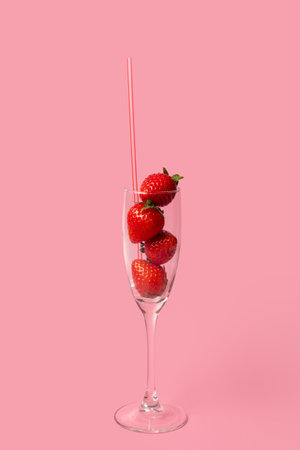 A glass glass full of red ripe strawberries and a tube isolated on a pink background. Summer drinks. Summer cocktail. Healthy fruit drinksの写真素材