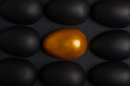 A creative designer postcard made of rows of halves of black eggs and a golden egg in the center. An exquisite Easter card .の写真素材