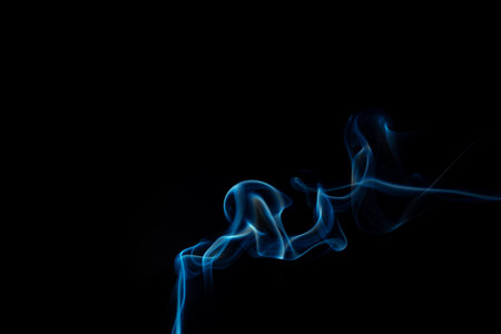 Wispy blue smoke wave flowing against a black background, creating a sense of mystery and elegance. Abstract and atmospheric concept. Swirling, writhing smoke to overlay on your photos.の写真素材