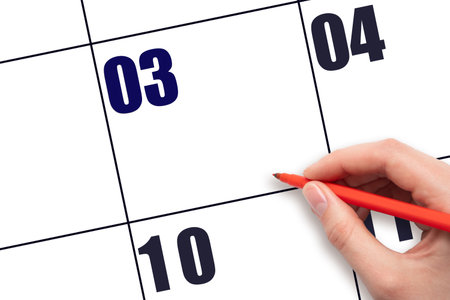 Calendar date 3. A hand holding a red pen is about to write text on an empty white calendar page with the date 3 without a month. Mockup. Save the date. Holiday.  Planning or scheduling concept.の写真素材