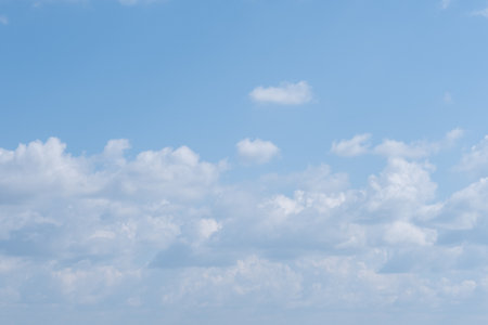 Fluffy white clouds scattered across bright blue sky on sunny day. concept of peace and calm.