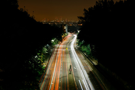 Aerial view of traffic light trails going into London, city skyline on the background.