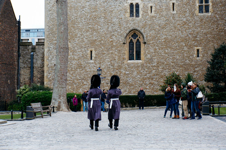 LONDON, UK - MARCH 30, 2016: Tourists watch two Queen's Guards in winter dress marching on the grounds of the Tower of London.のeditorial素材