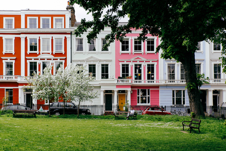 LONDON, UK - MAY 17, 2016: Man reading in Chalcot Square Gardens, colourful terraced houses of Primrose Hill on the background. Primrose Hill is one of the most expensive residential areas in Londonのeditorial素材