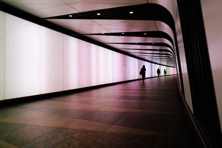 LONDON, UK - MAY 17, 2016: People walking through futuristic looking pedestrian tunnel featuring an LED integrated light wall in Granary Square exit from Kings Cross Underground station.のeditorial素材