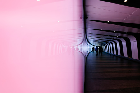 LONDON, UK - MAY 17, 2016: Reflection of people walking through futuristic looking pedestrian tunnel featuring an LED integrated light wall in Granary Square exit from Kings Cross Underground station.のeditorial素材