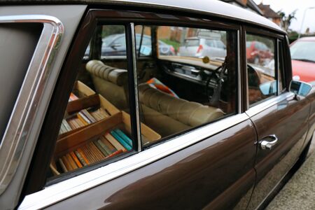 Old car with boxes of books inside parked on a street on a bright day