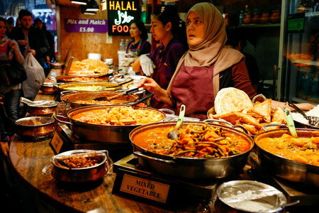 Traders at a market stall selling curry and varieties of cooked foods at Camden Market.のeditorial素材
