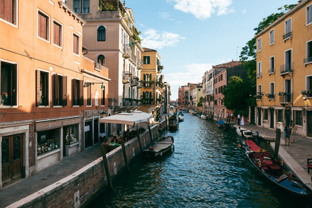 People alongside a canal in Venice on a sunny summer day. Venice is an popular tourist destination for its uniqueness and celebrated art and architecture.のeditorial素材