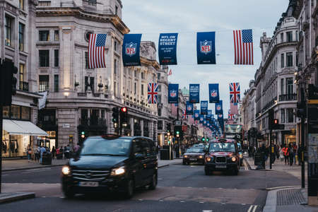 Black taxi and cars on Regent Street, London. The street is decorated with NFL flags to celebrate the event and four NFL games played in capital in 2017.のeditorial素材