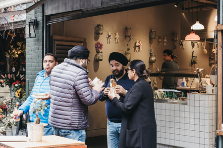 People standing, eating food purchased at Borough Market, one of the largest and oldest food markets in London.のeditorial素材