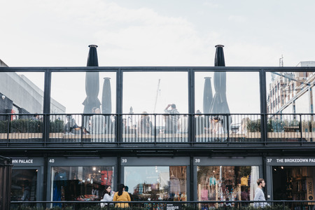 People walking past and sitting at the roof cafe at BOXPARK Shoreditch, shipping container, pop-up mall for independent and fashion and lifestyle stores and cafes.のeditorial素材