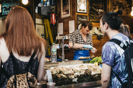 Seller and customer at an oyster bar in Borough Market, one of the largest and oldest food markets in London.のeditorial素材