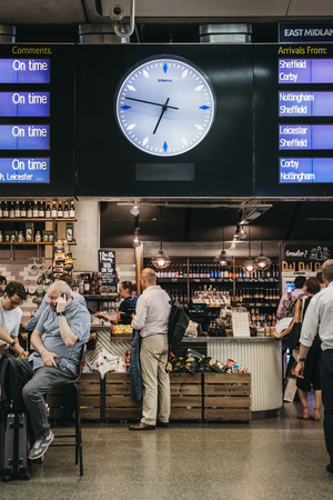 People buying food at a cafe, waiting for their trains under the departure board inside St. Pancras station, one of the largest railway stations in London and a home to Eurのeditorial素材