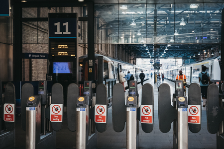 People walking towards the train on a platform at King's Cross station, one of the largest railway...