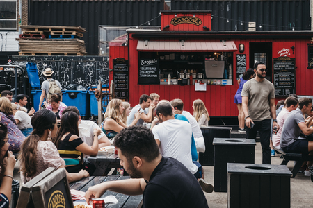 People enjoying street food in Ely's Yard, a popular industrial-style street food market just off...