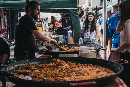 London, UK - July 21, 2018: People buying food from a market stall in Portobello Road Market, Notting Hill, London. Portobello Road is the worldâs largest antiques market with over 1,000 dealers .のeditorial素材