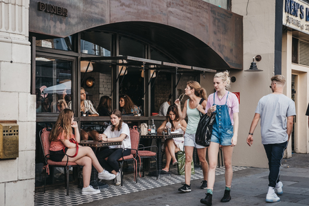 London, UK - July 21, 2018: People sitting at outdoor tables of Diner in Portobello Road Market, one...