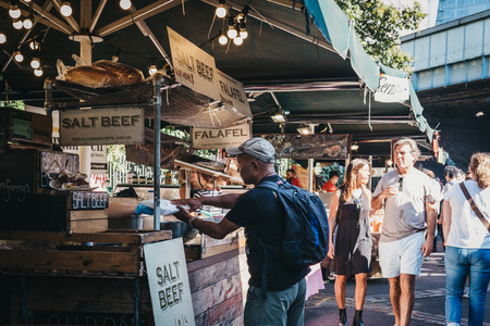 London, UK - September 17, 2018: Man buying salt beef sandwich from Nana Fanny's market stand in Borough Market, one of the largest and oldest food markets in London.のeditorial素材