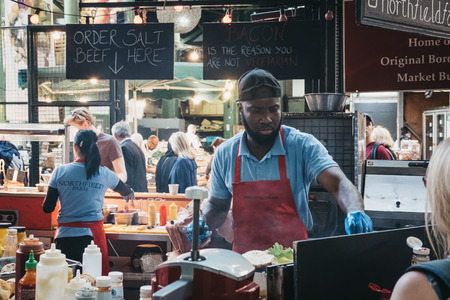 London, UK - September 17, 2018: Staff preparing food at Northfield Butchery market stand in Borough...