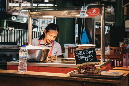 London, UK - September 17, 2018: Hot salt beef sandwich on a food stand in Borough Market, seller on the background. Borough Market is one of the largest and oldest food markets in London.のeditorial素材